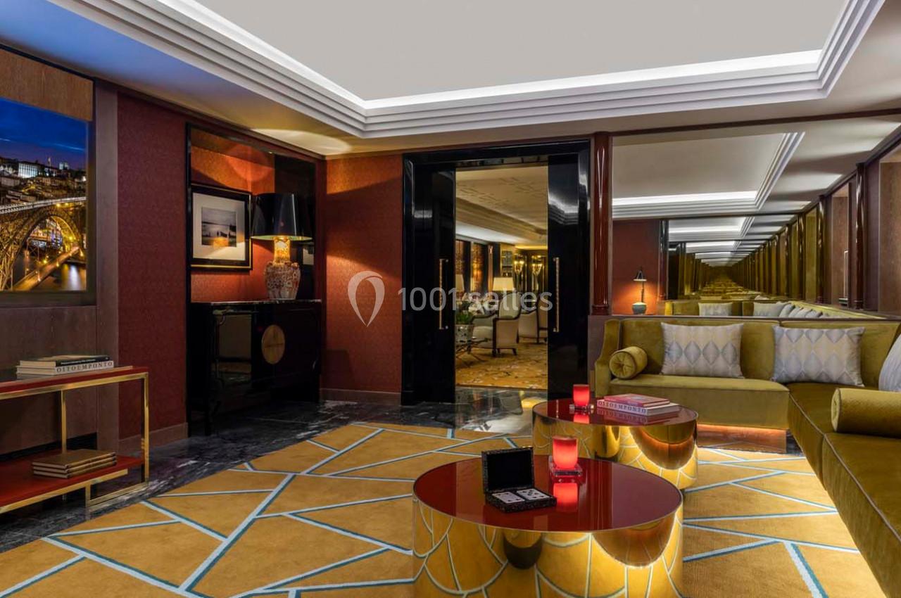 Salon élégant avec canapé jaune, tables basses rouges, éclairage tamisé et miroirs reflétant la pièce.