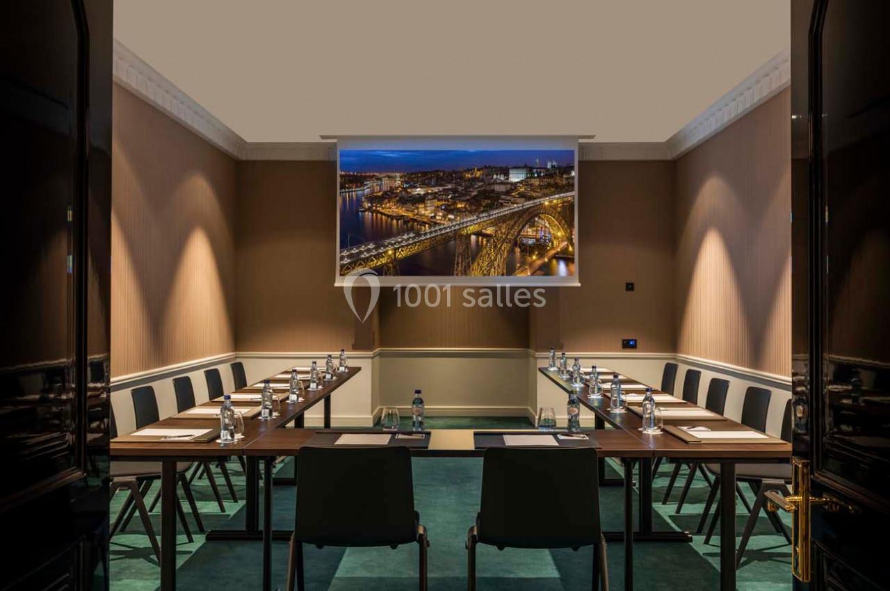 Salle de réunion aménagée avec une table en U, des chaises et un écran projetant une vue nocturne urbaine.