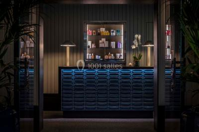 Salle de soins avec table de massage, produits de beauté, serviettes pliées, plantes et éclairage tamisé.