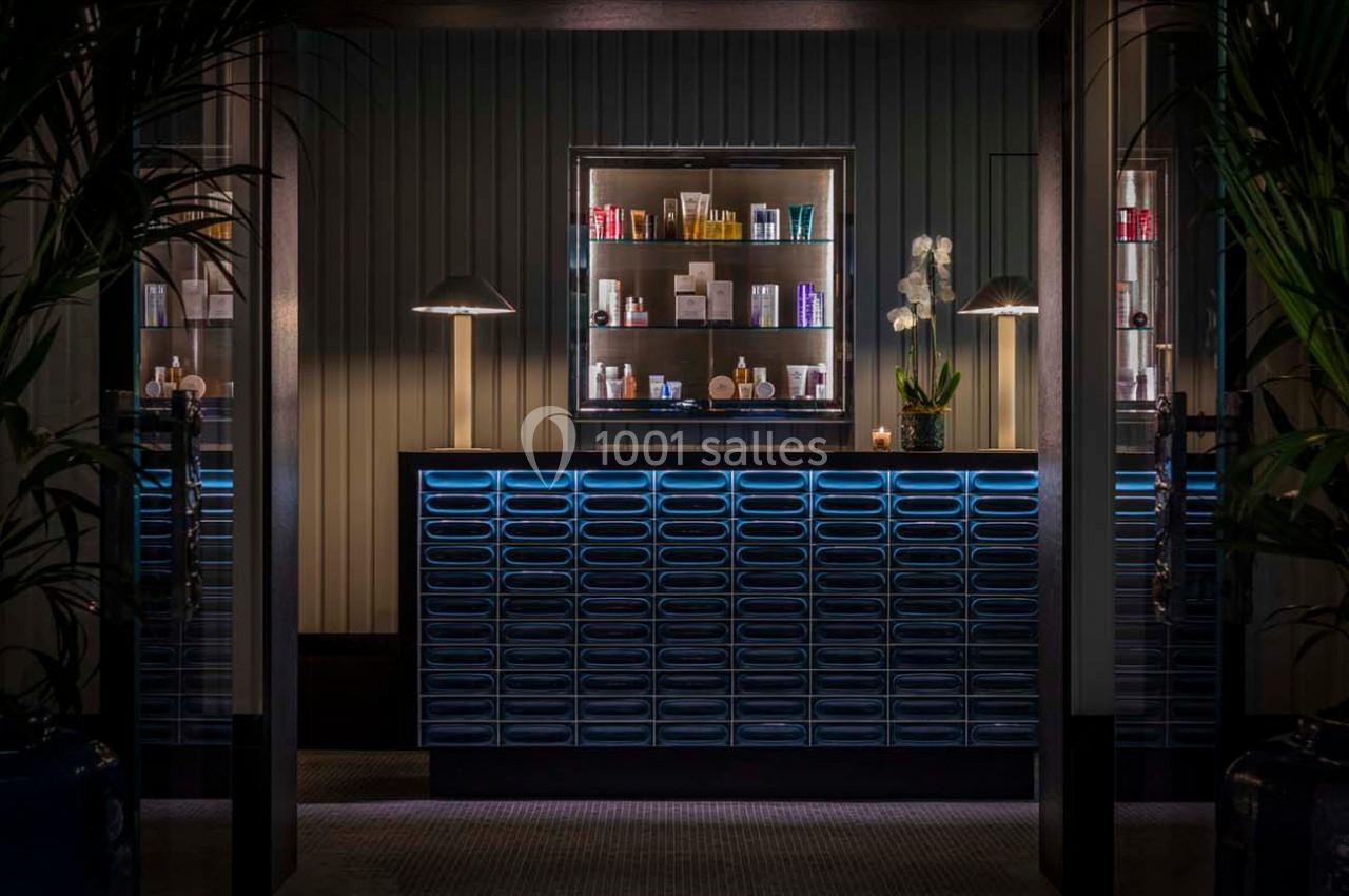 Comptoir moderne éclairé avec des étagères de produits de soin, entouré de plantes et d'une lumière tamisée.