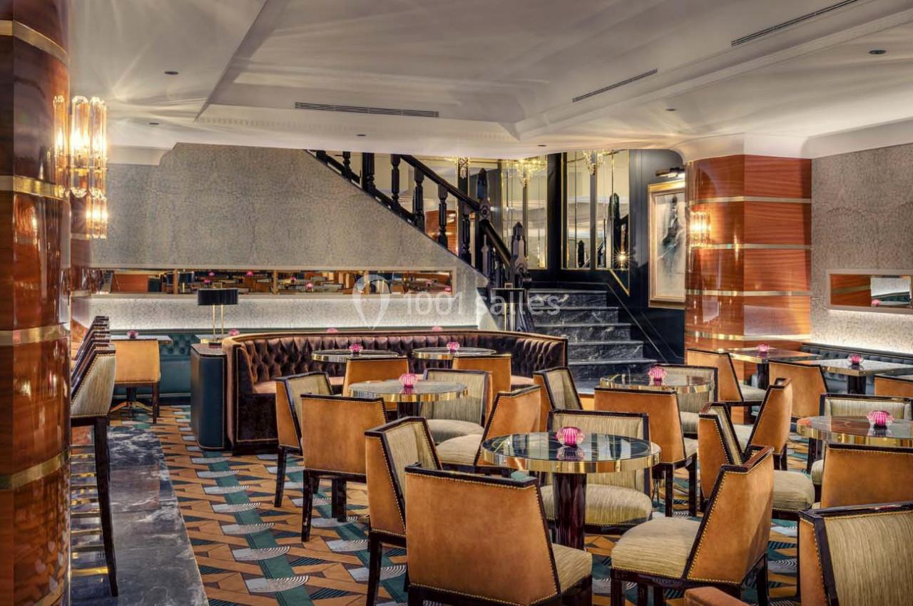 Salle de restaurant élégante avec des tables rondes, des chaises rembourrées et un éclairage chaleureux.