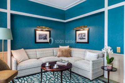 Salle de soins avec table de massage, produits de beauté, serviettes pliées, plantes et éclairage tamisé.