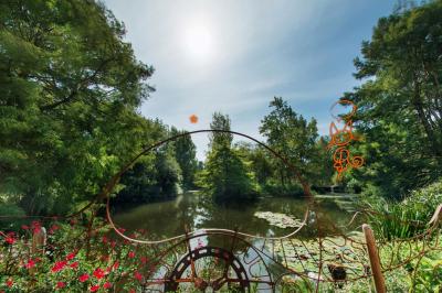 Jardin verdoyant avec des palmiers, des pins et des buissons sous un ciel ensoleillé, décoré de dessins orange.