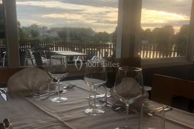 Chambre avec un lit double, draps gris, deux tables de chevet en bois, mur gris et sol en parquet clair.