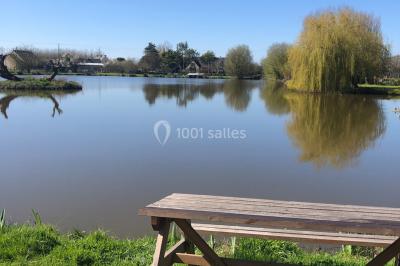 Chambre avec un lit double, draps gris, deux tables de chevet en bois, mur gris et sol en parquet clair.