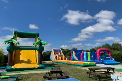 Chambre avec un lit double, draps gris, deux tables de chevet en bois, mur gris et sol en parquet clair.