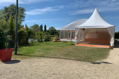 Chambre avec un lit double, draps gris, deux tables de chevet en bois, mur gris et sol en parquet clair.