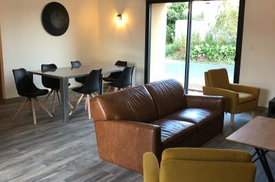 Chambre avec un lit double, draps gris, deux tables de chevet en bois, mur gris et sol en parquet clair.