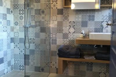 Chambre avec un lit double, draps gris, deux tables de chevet en bois, mur gris et sol en parquet clair.