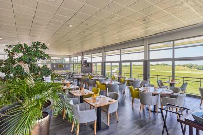 Salle intérieure avec simulateurs de golf, zone d'entraînement au putting et équipements sportifs modernes.
