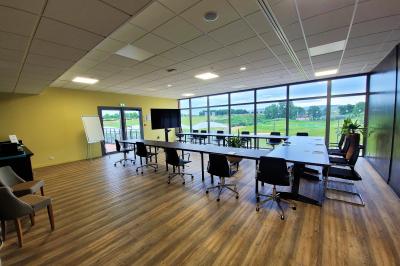 Salle intérieure avec simulateurs de golf, zone d'entraînement au putting et équipements sportifs modernes.