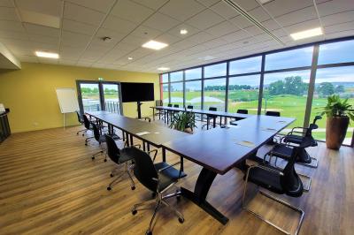 Salle intérieure avec simulateurs de golf, zone d'entraînement au putting et équipements sportifs modernes.