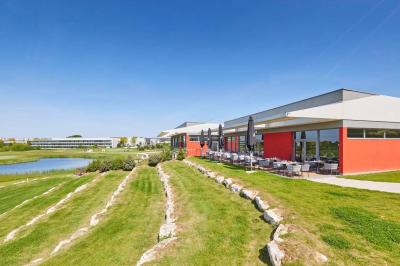 Salle de réception décorée avec des tables dressées, des chaises ornées de nœuds roses et des bouquets de fleurs.