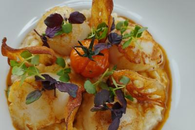 Salle de réception décorée avec des tables dressées, des chaises ornées de nœuds roses et des bouquets de fleurs.
