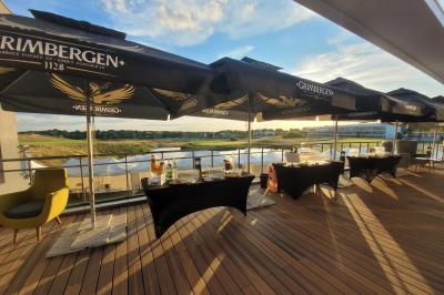 Salle de réception décorée avec des tables dressées, des chaises ornées de nœuds roses et des bouquets de fleurs.