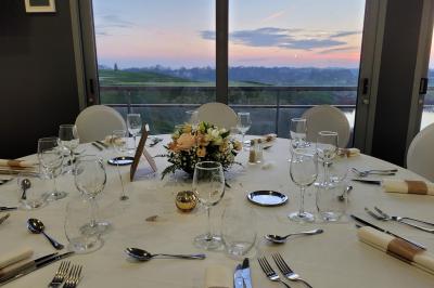 Salle de réception décorée avec des tables dressées, des chaises ornées de nœuds roses et des bouquets de fleurs.