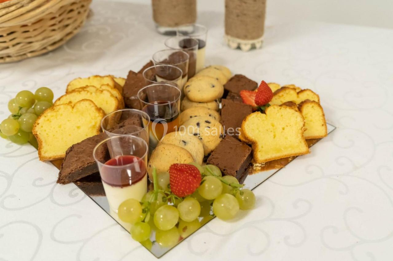 Plateau de desserts variés avec gâteaux, brownies, cookies, verrines, raisins et fraises sur une nappe blanche.