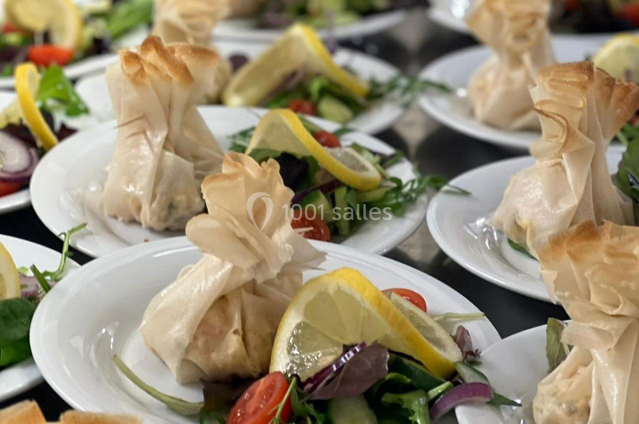 Assiettes garnies de feuilletés en aumônière accompagnés de salade verte, tomates cerises et tranches de citron.