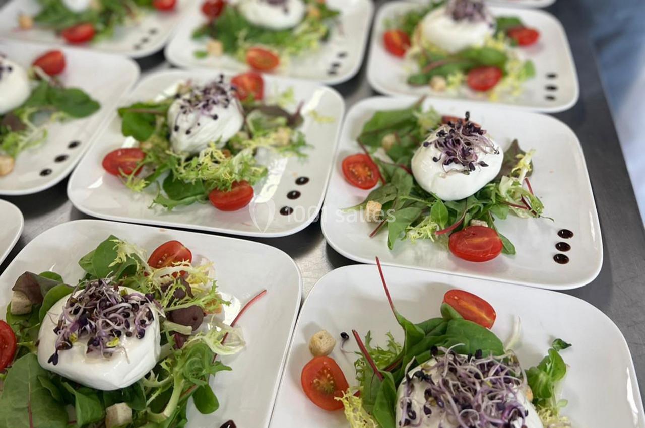 Assiettes de salade composée avec burrata, tomates cerises, jeunes pousses, croûtons et filet de vinaigre balsamique.