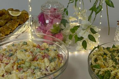Assiettes de pastillas saupoudrées de sucre glace, accompagnées de salade verte, légumes frais et fleurs comestibles.