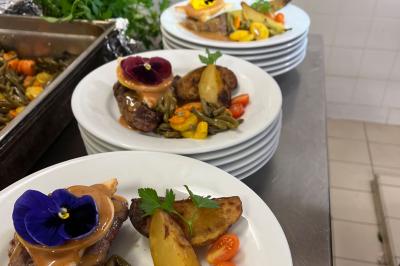 Assiettes de pastillas saupoudrées de sucre glace, accompagnées de salade verte, légumes frais et fleurs comestibles.