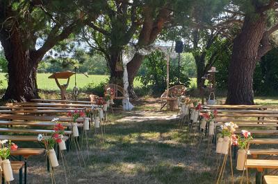 Tente blanche montée sur une pelouse, équipée de tables hautes, devant un bâtiment clair et des arbres.