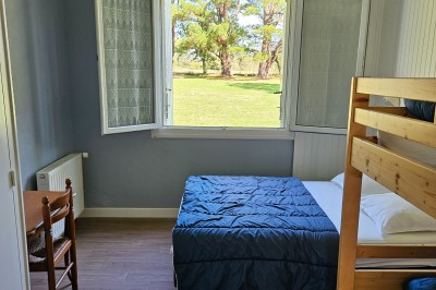 Tente blanche montée sur une pelouse, équipée de tables hautes, devant un bâtiment clair et des arbres.