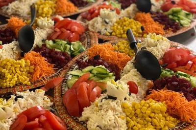 Assiettes de pastillas saupoudrées de sucre glace, accompagnées de salade verte, légumes frais et fleurs comestibles.