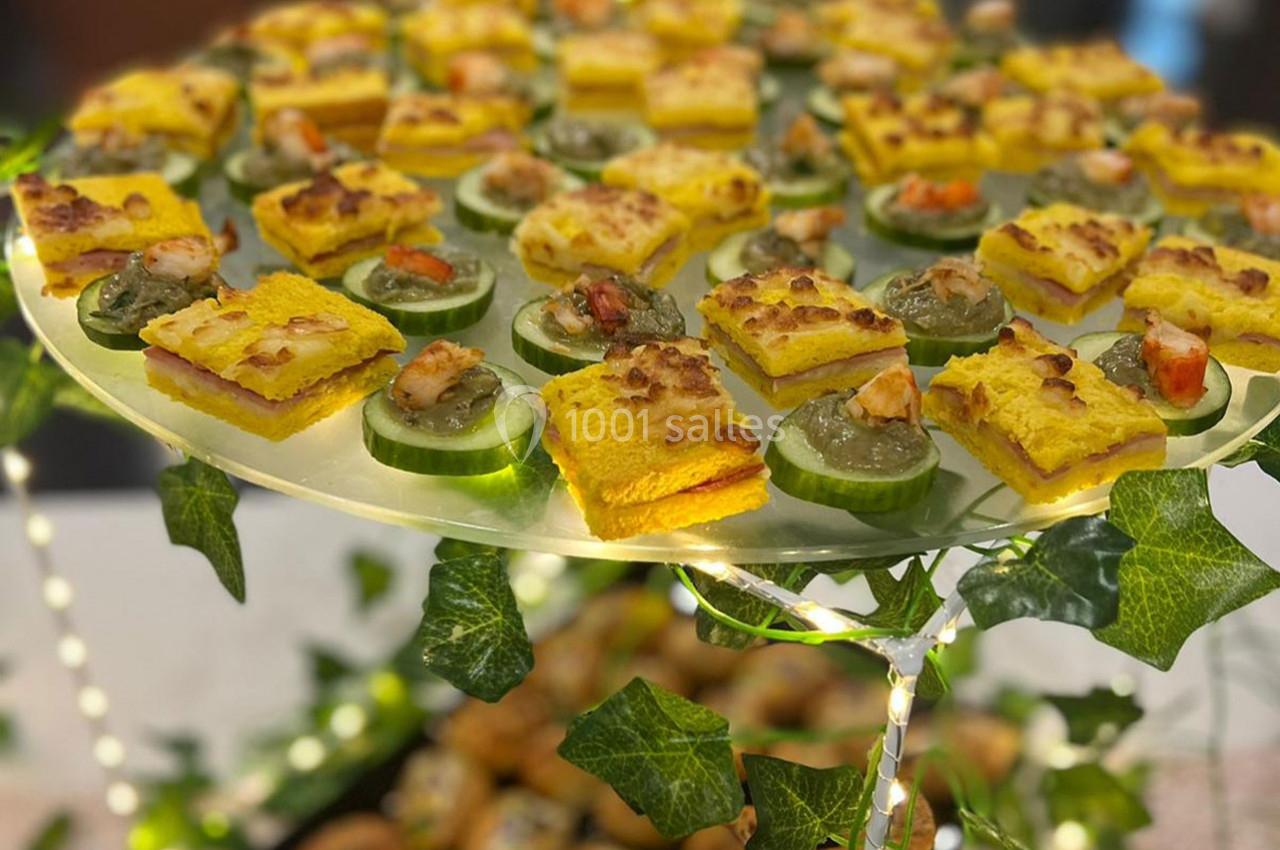 Plateau de bouchées apéritives comprenant des toasts garnis et des rondelles de concombre avec des crevettes.