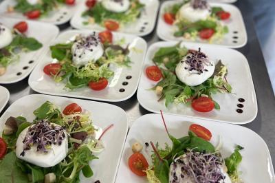 Assiettes de pastillas saupoudrées de sucre glace, accompagnées de salade verte, légumes frais et fleurs comestibles.
