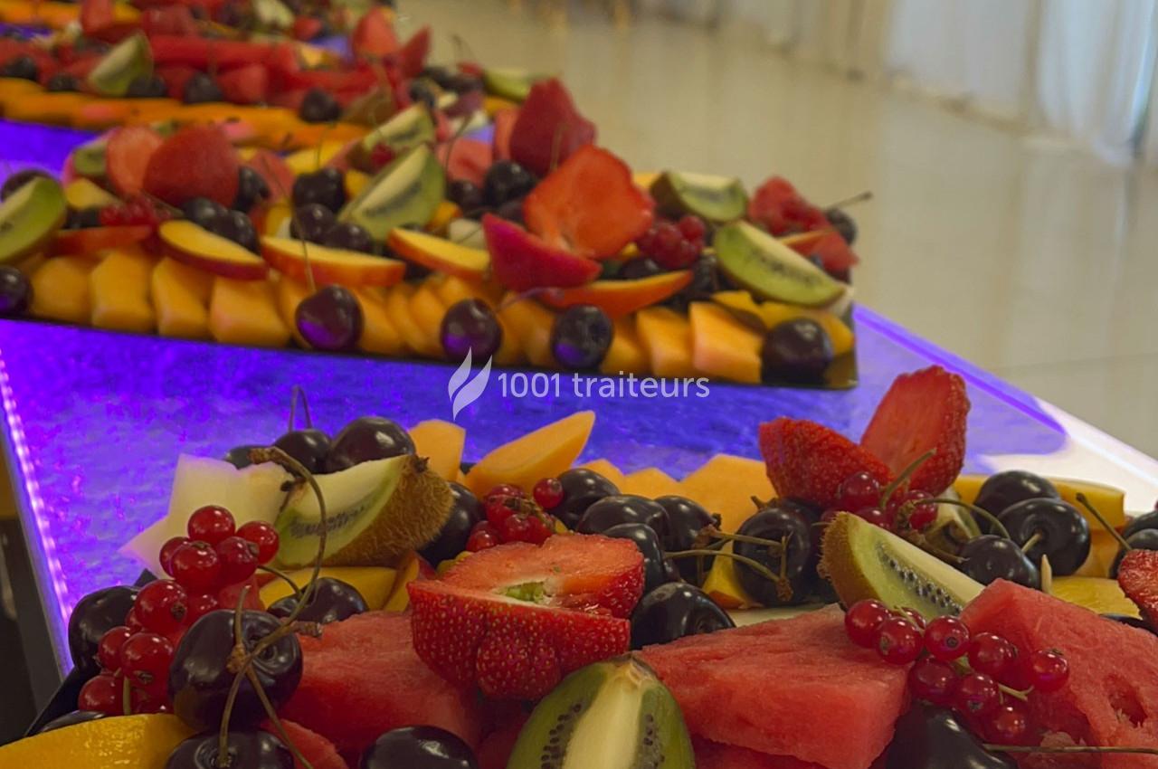 Plateaux de fruits frais variés comprenant pastèque, fraises, kiwis, cerises et groseilles, disposés sur une table lumineuse.