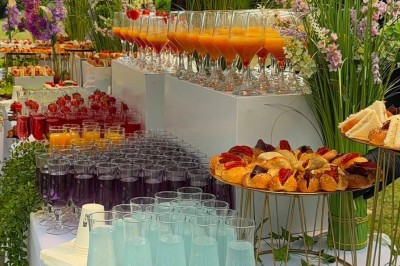 Miniature Traiteur Beauchamp (Val-d'Oise) - L'instant Gourmand #16 Buffet en extérieur avec brochettes, cocktails colorés, viennoiseries et décor floral sur une table blanche.