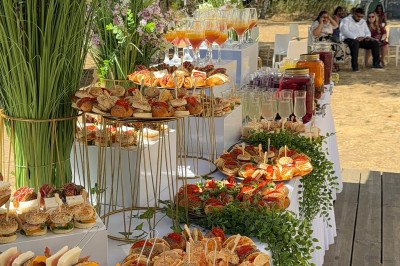 Miniature Traiteur Beauchamp (Val-d'Oise) - L'instant Gourmand #10 Buffet en extérieur avec brochettes, cocktails colorés, viennoiseries et décor floral sur une table blanche.