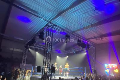 Salle équipée de plusieurs écrans, éclairages bleus et matériel audiovisuel, prête pour un événement ou une présentation.