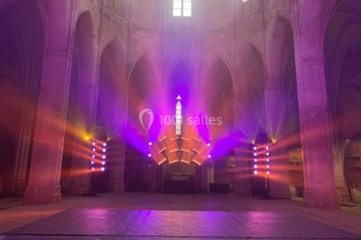 Salle équipée de plusieurs écrans, éclairages bleus et matériel audiovisuel, prête pour un événement ou une présentation.
