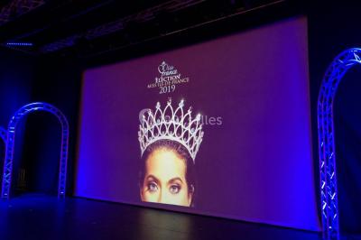 Salle équipée de plusieurs écrans, éclairages bleus et matériel audiovisuel, prête pour un événement ou une présentation.