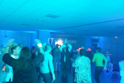 Groupe de personnes dansant sous des lumières colorées dans une salle avec un plafond industriel.
