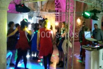 Groupe de personnes dansant sous des lumières colorées dans une salle avec un plafond industriel.