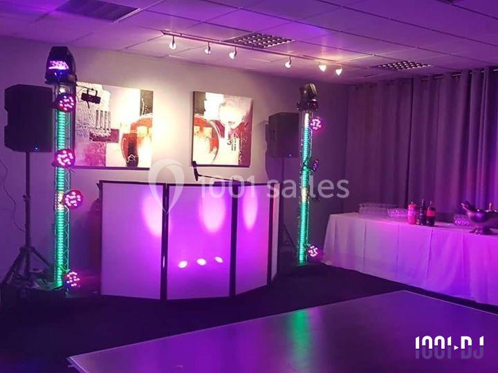 Installation de matériel de sonorisation et éclairage coloré dans une salle avec table de buffet à droite.