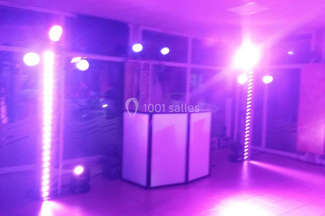 Éclairage violet avec projecteurs et colonnes lumineuses autour d'une console blanche dans une salle.