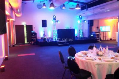 Groupe de personnes dansant sous des lumières colorées dans une salle avec un plafond industriel.