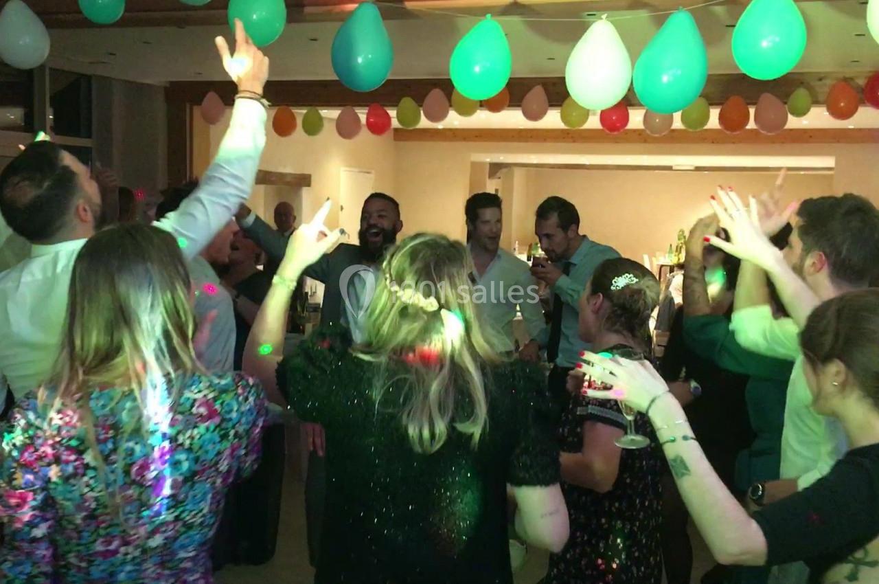 Des personnes dansent sous des ballons suspendus dans une salle décorée lors d'une fête animée.