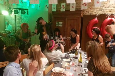 Groupe de personnes dans une salle éclairée par des lumières roses, certaines tenant des bougies.