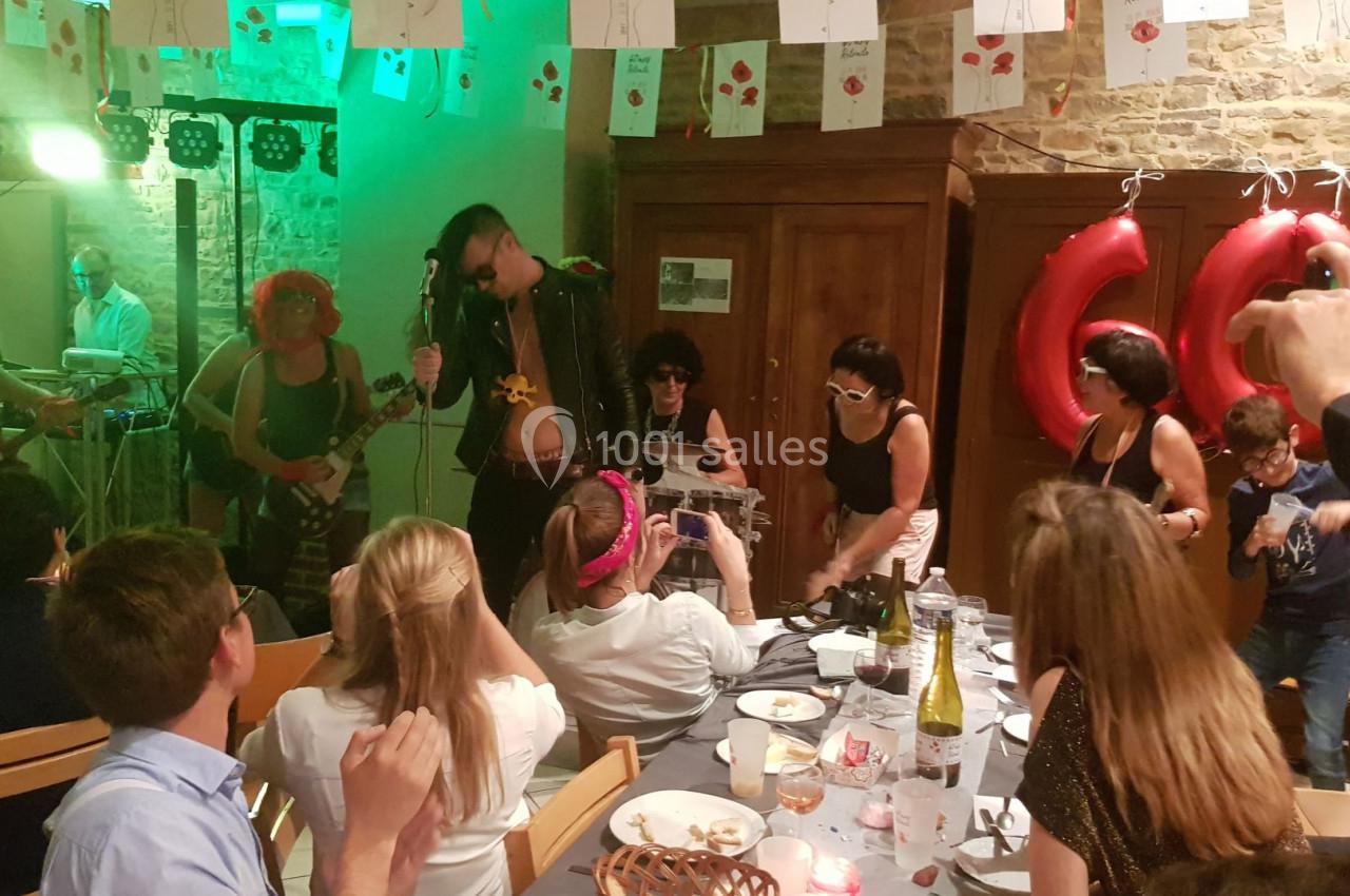 Des personnes costumées participent à une fête dans une salle décorée, avec des invités assis à table.