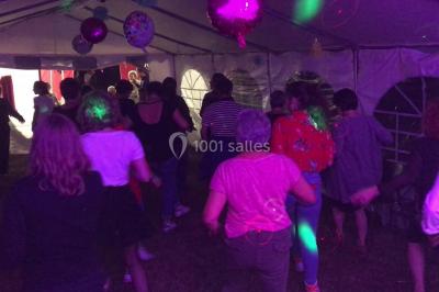Groupe de personnes dans une salle éclairée par des lumières roses, certaines tenant des bougies.