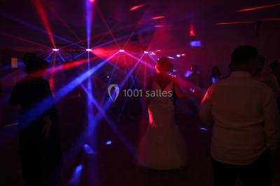 Groupe de personnes dans une salle éclairée par des lumières roses, certaines tenant des bougies.