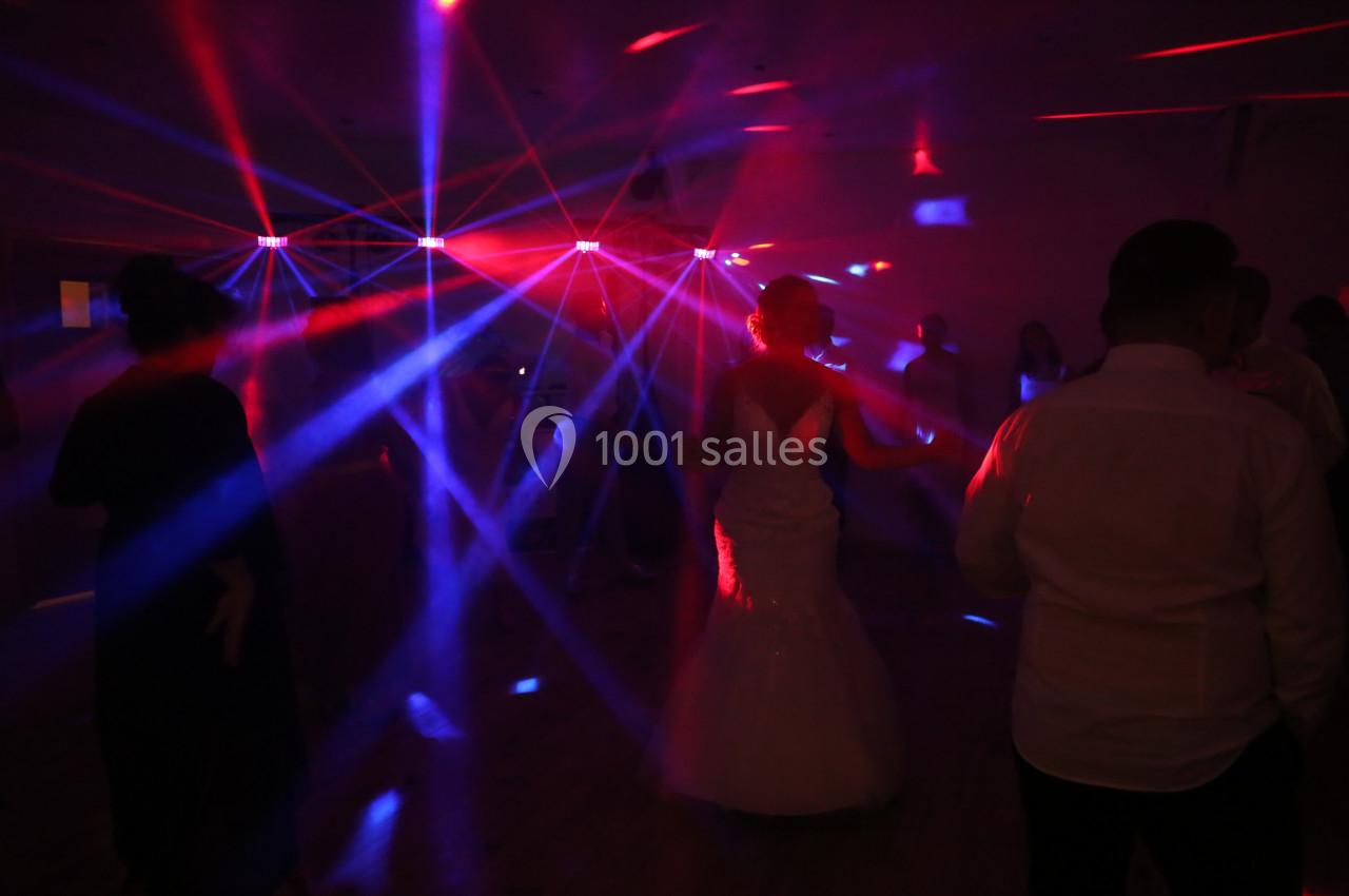 Des personnes dansent sous des lumières colorées et des faisceaux laser dans une ambiance festive.