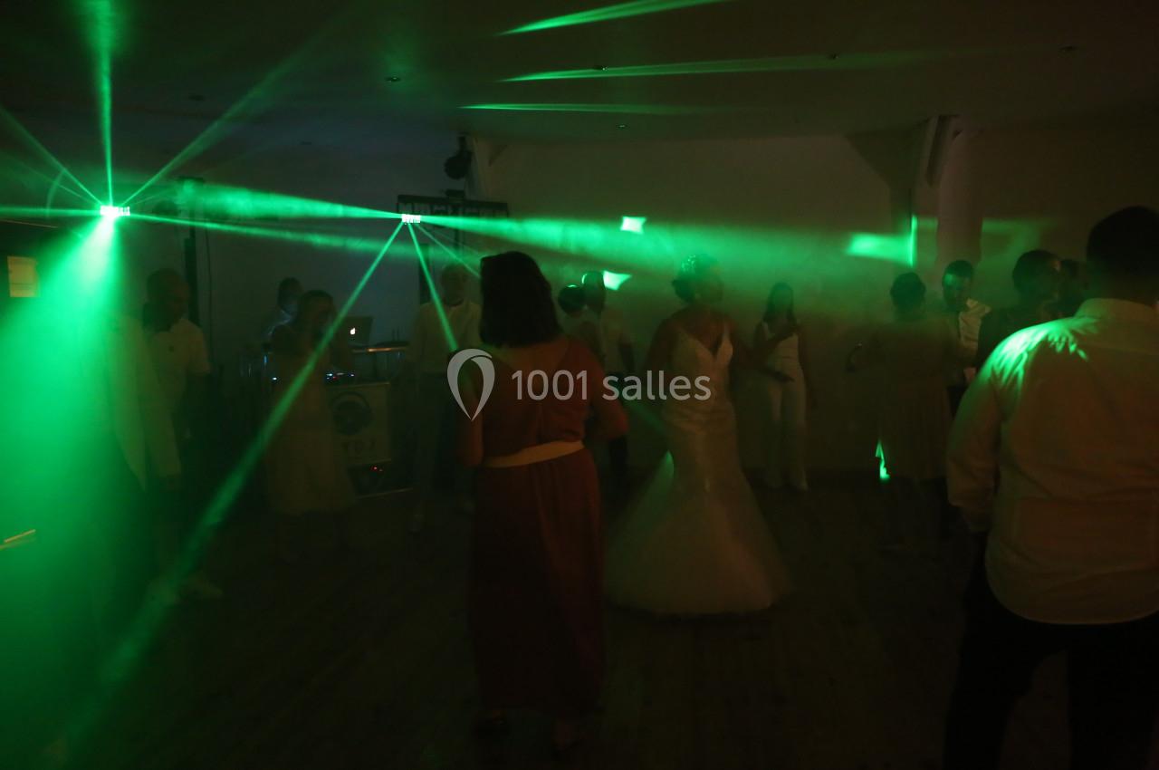 Des invités dansent sous des lumières vertes lors d'une soirée dans une salle sombre.