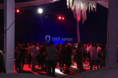 Groupe de personnes dans une salle éclairée par des lumières roses, certaines tenant des bougies.