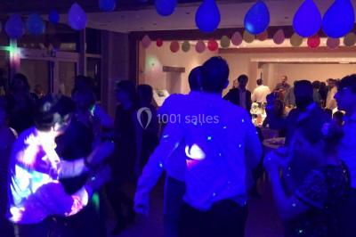 Groupe de personnes dans une salle éclairée par des lumières roses, certaines tenant des bougies.